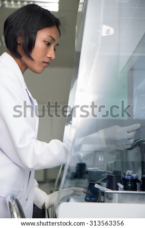technician works under safety hood of plastic in hospital laboratory