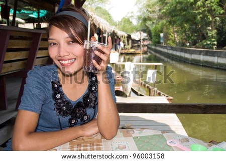 Young woman with drink sitting at a canal
