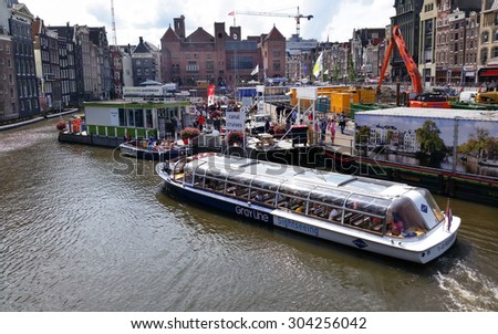 Boats on Amsterdam Canal \
Amsterdam, The Netherlands - August 15, 2014 : Wide angle view of Row Houses in Historic Part of Amsterdam, on a beautiful summer day. Tourists taking a sightseeing