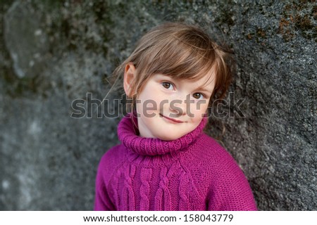 Portrait of a beautiful little girl with freckles in a fuchsia sweater
