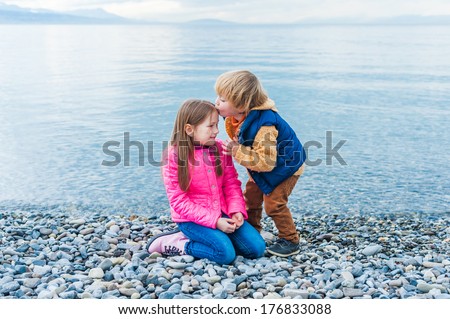 Brother and sister playing on a beach on a nice day in early spring