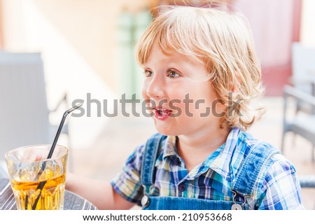 Adorable toddler boy drinking apple juice in a cafe