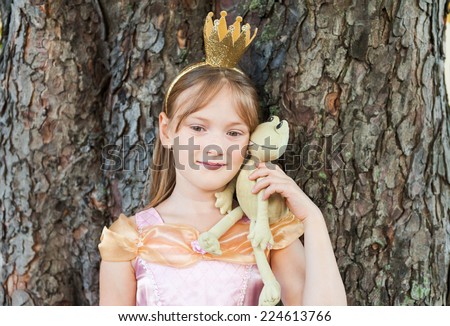 Cute little girl playing with a toy frog, pretending to be a princess