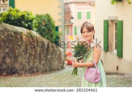 Outdoor portrait of a cute little girl with beautiful bouquet of small pink roses, toned image