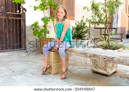 Portrait of a cute little girl resting in a typical old italian town