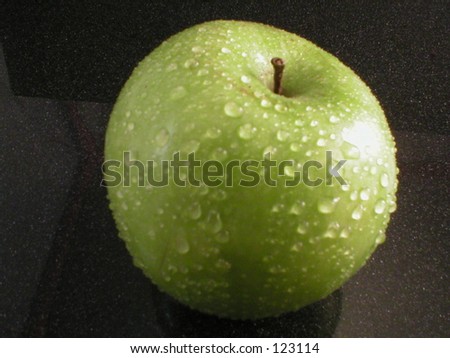Granny Smith apple with dew on black background.