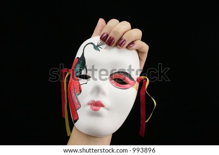 Young ladies hand holding Mardi Gras mask with black background.