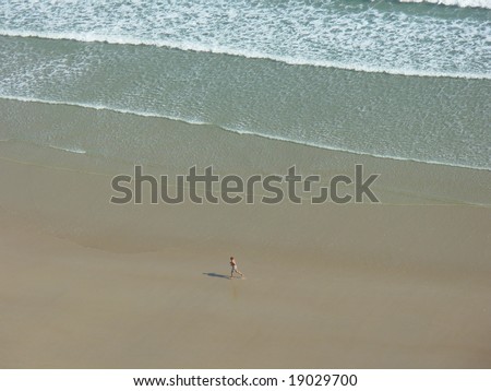man running on empty beach taken from above