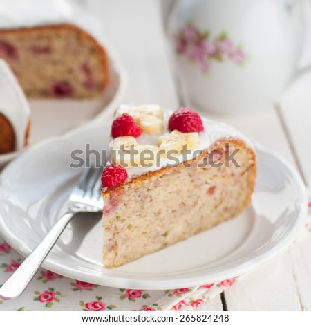 A Piece of Banana Cake with Sugar Glaze Topped with Raspberries and Banana Slices, copy space for your text, shallow dof