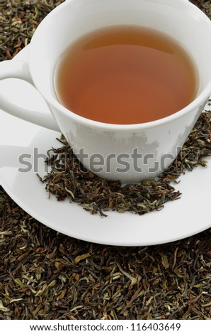 Closeup of a black tea standing on dried black tea leaves.