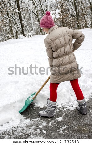 Young woman shoveling snow off street with green shovel.