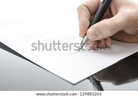 Detail of a male hand signing a contract on a black table.