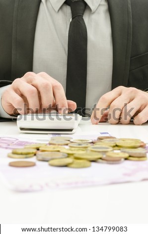 Close up of male accountant in suit calculating expenses. With Euro money on his desk.