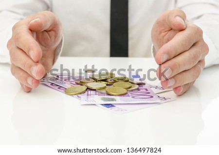 Male hands around Euro banknotes and coins as if they are giving power and energy to money.
