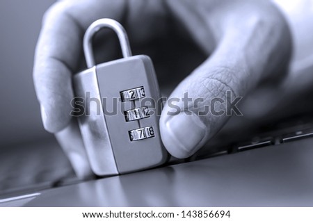 Male hand trying to break padlock on computer keyboard. Concept of internet piracy.