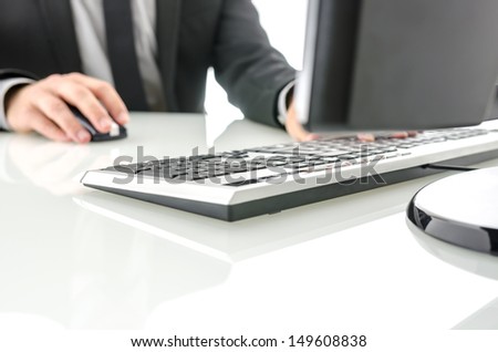 Man working on computer at white office desk.