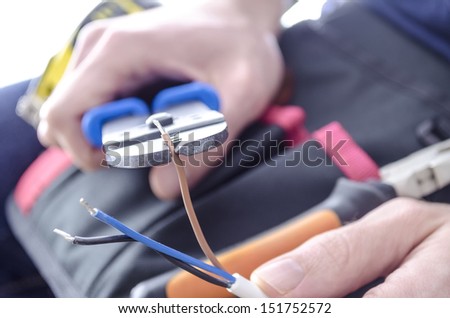 Closeup of worker\'s hands cutting electric wires with pliers.