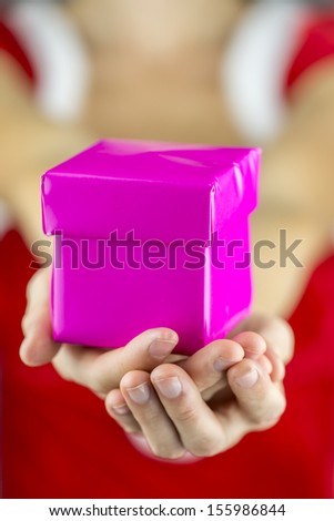 Closeup of female hands giving pink Christmas present.