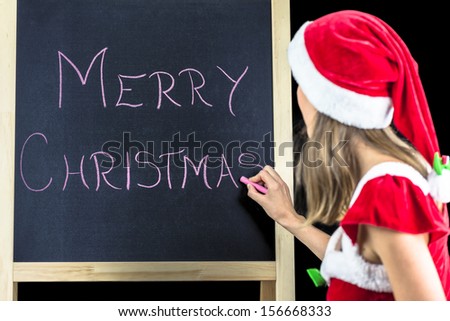 Miss Santa writing Merry Chrstmas on black board.