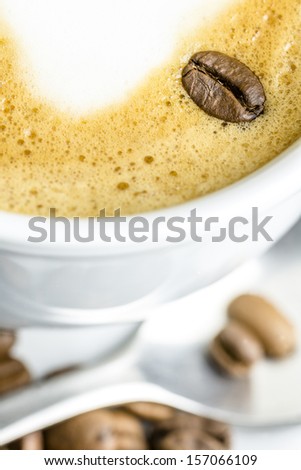 Closeup of coffee bean on cafe latte milk foam.