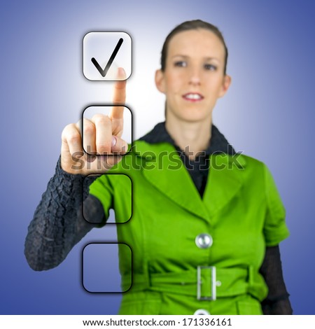 Woman completing check boxes with a tick on a virtual interface or touchscreen as she completes a survey or task indicating that it is successful or positive