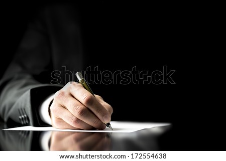 Businessman signing a document, taking notes, completing a questionnaire or writing correspondence, close up view of his hand and the paper
