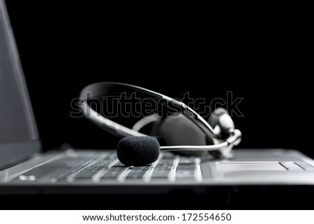 Low angle close up view of a headset lying on the keyboard of an open a laptop computer conceptual of hands free communication, client services or company support through a call center
