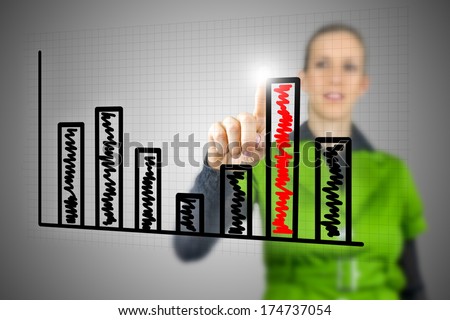 Young Caucasian woman touching with the finger the highest column of a vertical bar chart on an interactive virtual screen or interface