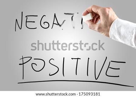 Man erasing Negative over Positive on a white screen in a conceptual image of opposing attitudes, attributes and qualities.
