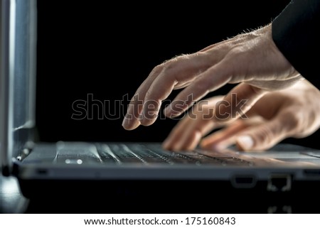 Businessman typing on his laptop computer entering information or answering correspondence, closeup low angle view of his hands.
