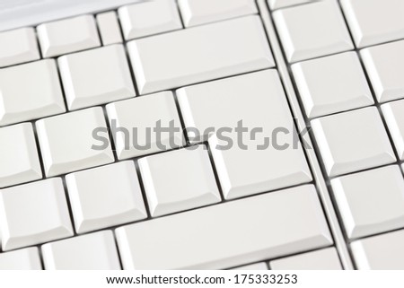 Closeup view from above of blank white keys on a computer keyboard with focus to three larger keys.