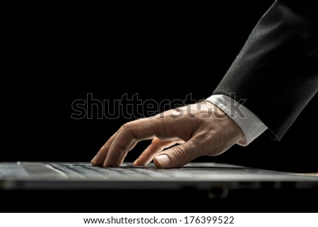 Closeup low angle view of the hand of a businessman in a suit using a laptop computer surfing the internet or typing in information during a business communication.