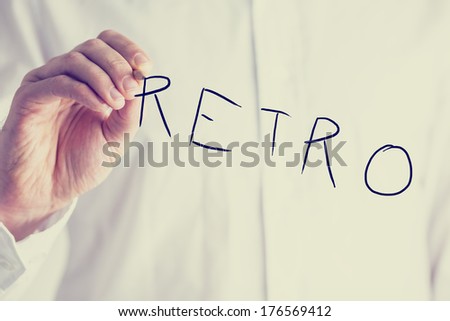 Vintage faded effect image of a man in a white shirt writing the word - Retro - on a virtual screen, closeup torso view with copyspace.