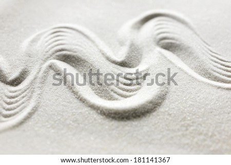 Organic wavy undulating pattern drawn in a Japanese yen garden, landscaped rock garden or raked sand with a grainy texture and flowing motion conceptual of tranquility and spirituality.