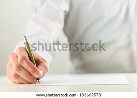 Close up of the hand of a man writing with a fountain pen on a sheet of blank white paper or document in a conceptual image.