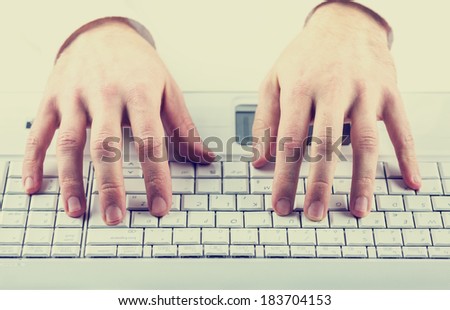 Toned instagram effect image of a man typing on a computer keyboard inputting data or information.