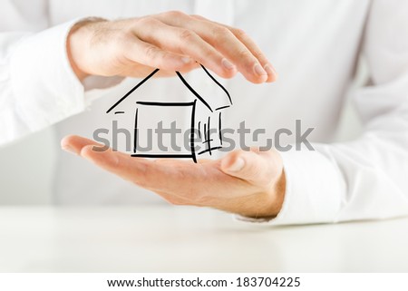 Man protecting a hand sketched outline of a house with his hands conceptual of ownership, insurance, security and risk, closeup of his hands against his white shirt.