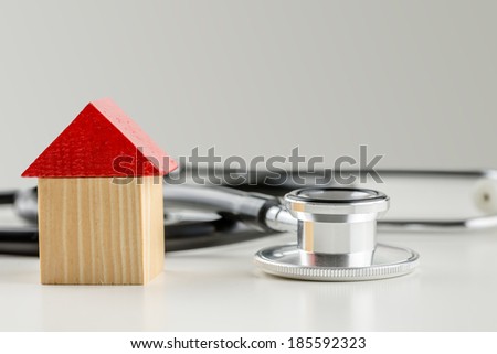 Wooden toy house next to a stethoscope. Conceptual image of solution to the real estate market crisis.