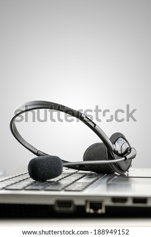 Headset on laptop computer conceptual of telemarketing, customer service or online help. Isolated over grey background.