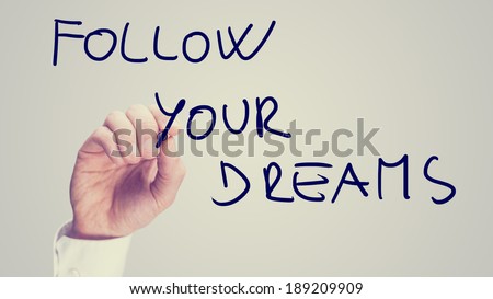 Retro instagram style image of a male hand writing motivational message Follow your dreams on virtual board.