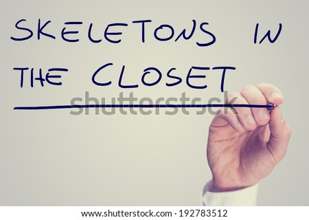 Male hand writing phrase Skeletons in the closet on a virtual screen.