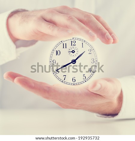Retro image of male hands making a protective gesture around clock face with white shining coming from behind it.