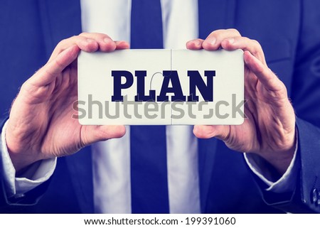 Retro instagram style image of man in an elegant suit holding white card with word Plan on it. Conceptual of life, business or education plan.