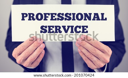 Closeup of businessman holding Professional service sign towards you, vintage effect toned image.