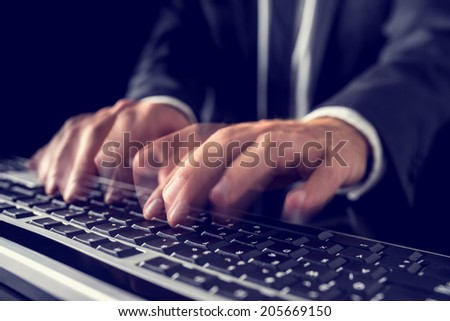 Closeup of the hands of a businessman in a suit typing on a computer keyboard inputting data with motion blur, retro effect faded look.