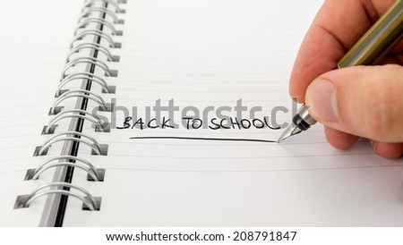 Man writing - Back to School - with a fountain pen in a ring bound journal or notebook as a reminder, conceptual image with copyspace.