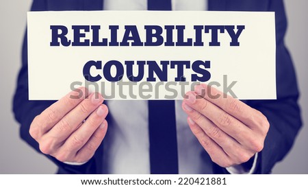 Close Up of Businessman Holding Sign Reading Reliability Counts.