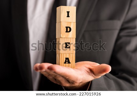 Businessman holding four wooden cubes, with the word Idea, concept of creative ideas.