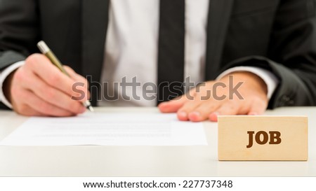 Close up Job Text on Small Wooden Piece in Front Businessman while Writing on White Table. A Simple Job Concept.