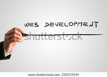 Businessman writing Web development with a black marker pen on a virtual screen over grey with plenty of copyspace.